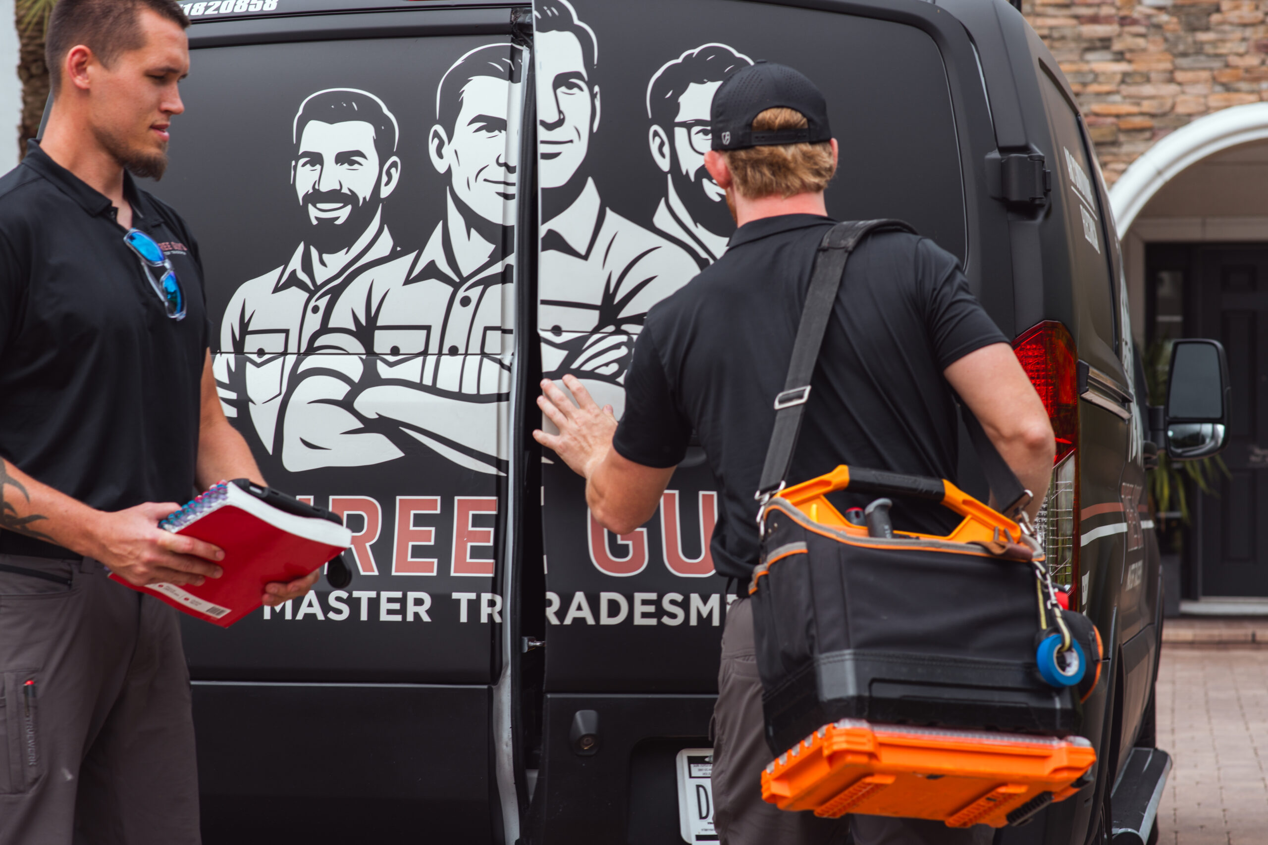 Three Guys Master Tradesmen technicians getting tools from the company van