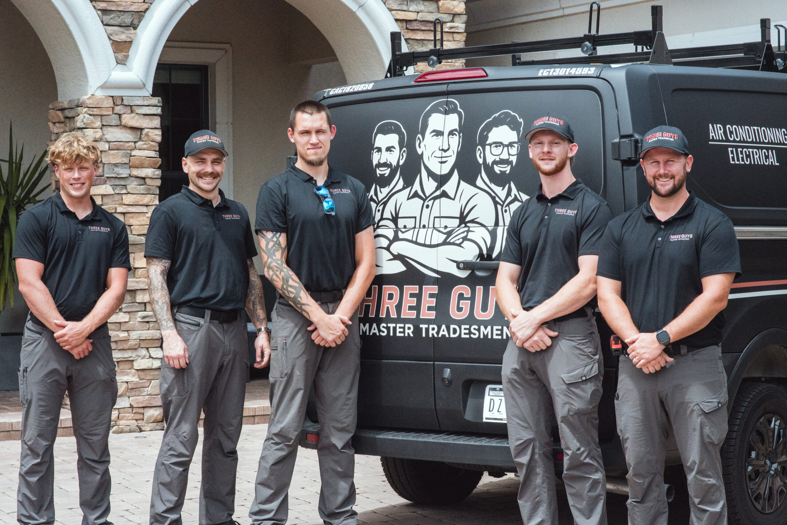 Three Guys Master Tradesmen HVAC and electrical team standing in front of a company service van