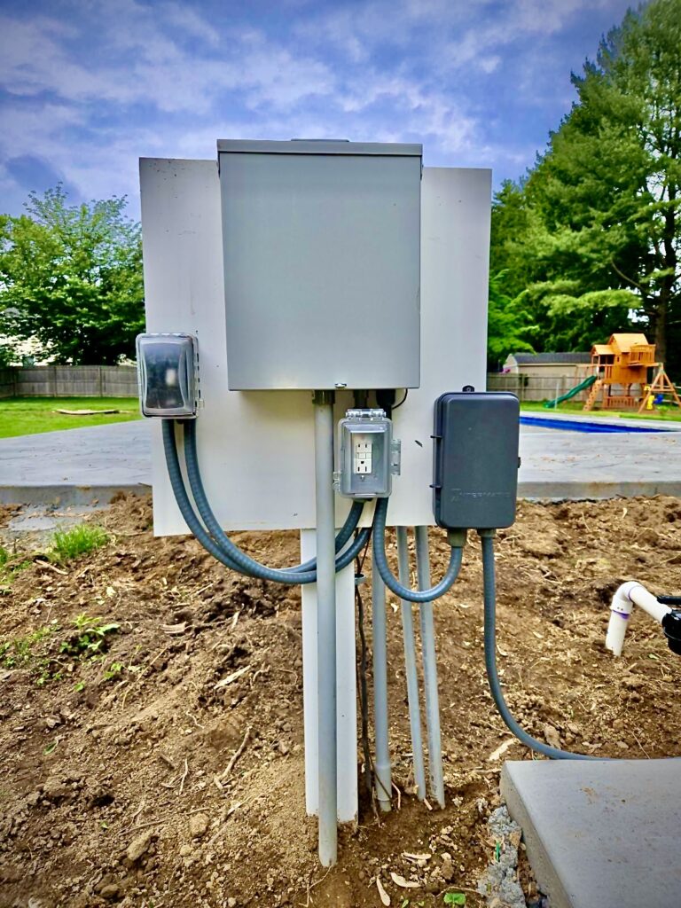 Pool electrical panel with disconnect boxes and GFCI outlet installed near backyard pool
