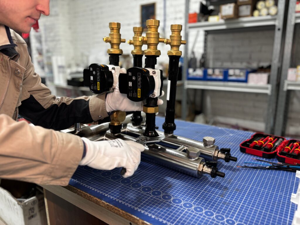 Technician assembling a brass heating manifold in a plumbing workshop