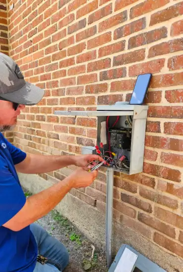 Three Guys electrician wiring a pool equipment control box on an outdoor wall