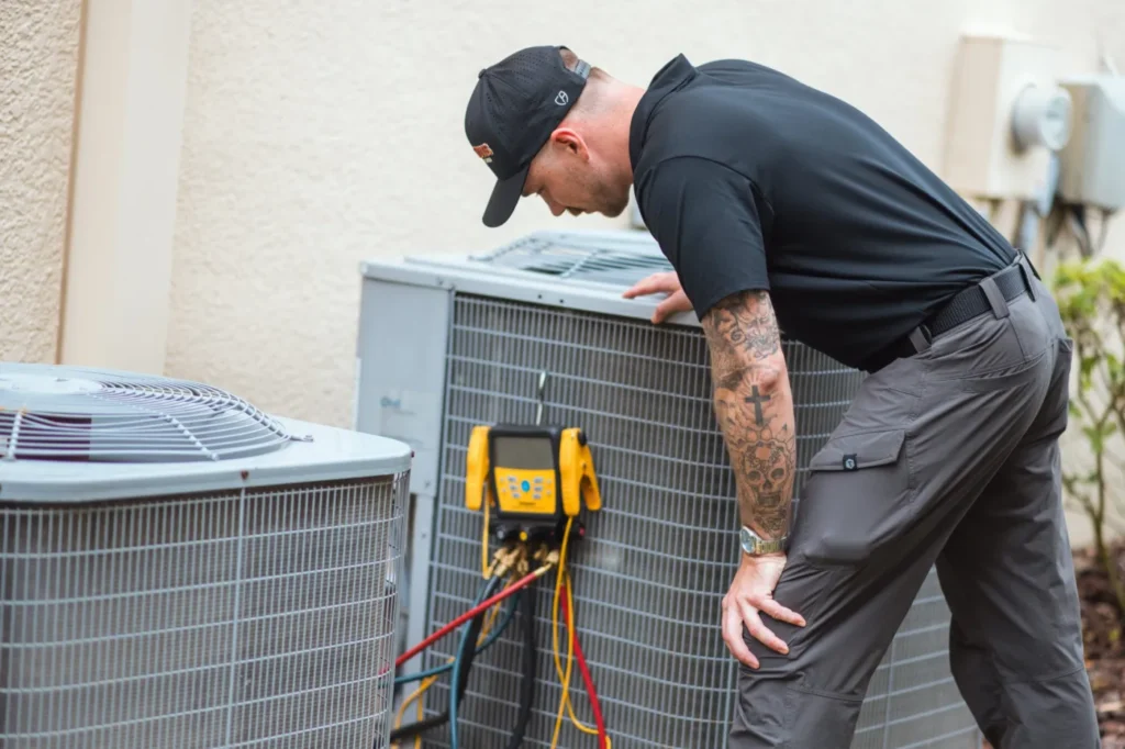 Three Guys HVAC technician checking refrigerant pressures with digital gauges on a Carrier AC condenser