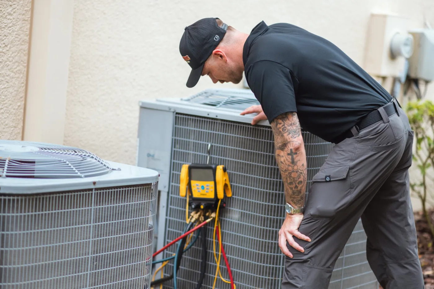 Three Guys HVAC technician checking refrigerant pressures with digital gauges on a Carrier AC condenser