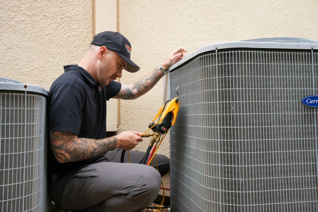 Three Guys HVAC technician inspecting an outdoor AC condenser with refrigerant gauges connected
