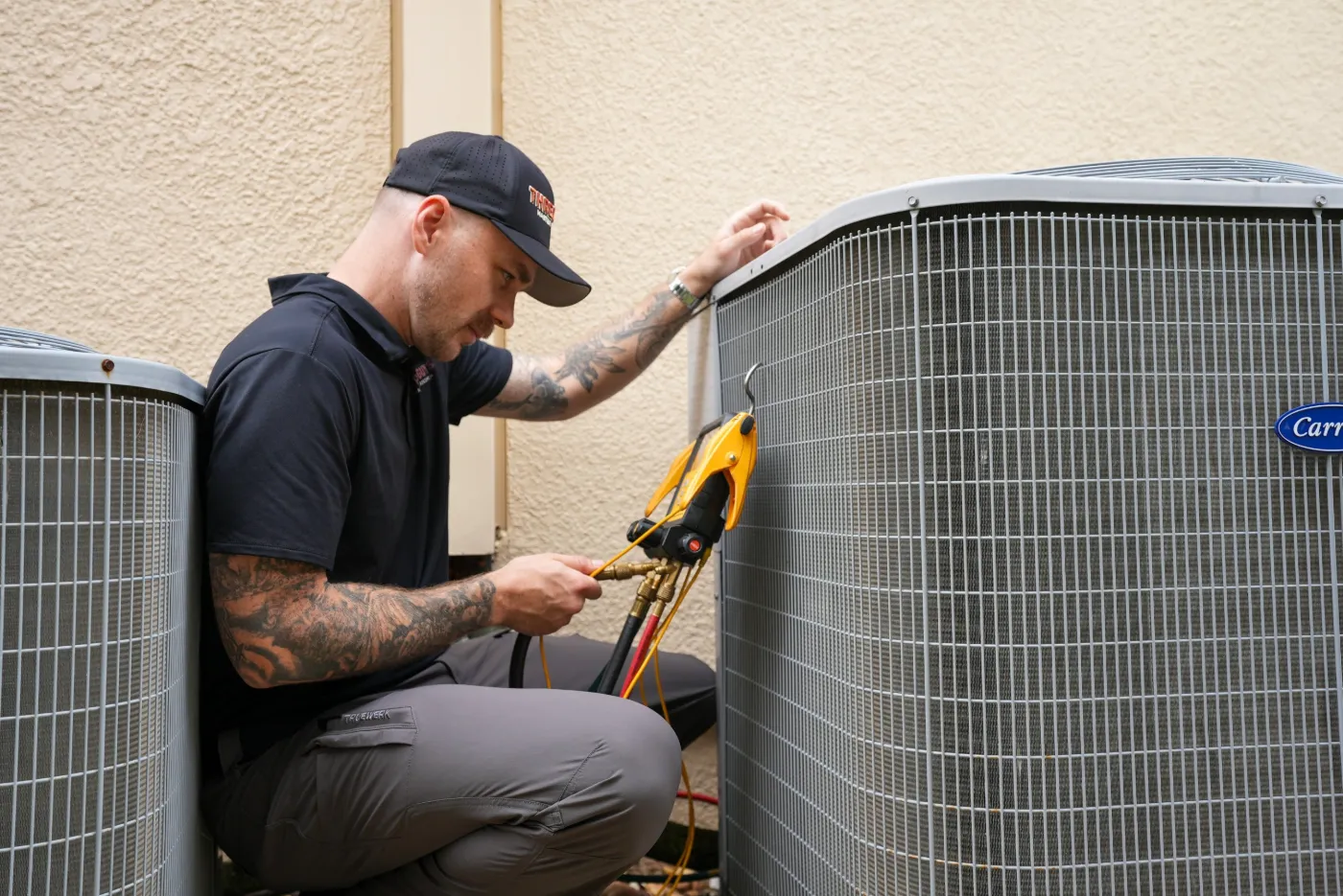 Three Guys HVAC technician inspecting an outdoor AC condenser with refrigerant gauges connected